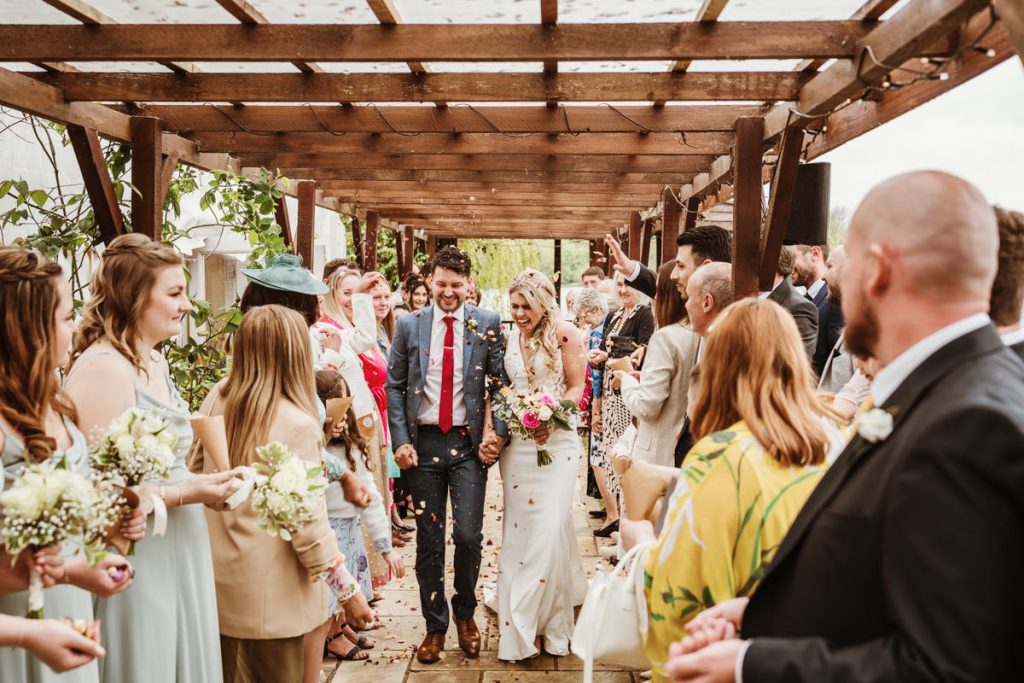 Bride and groom walking through confetti tunnel.