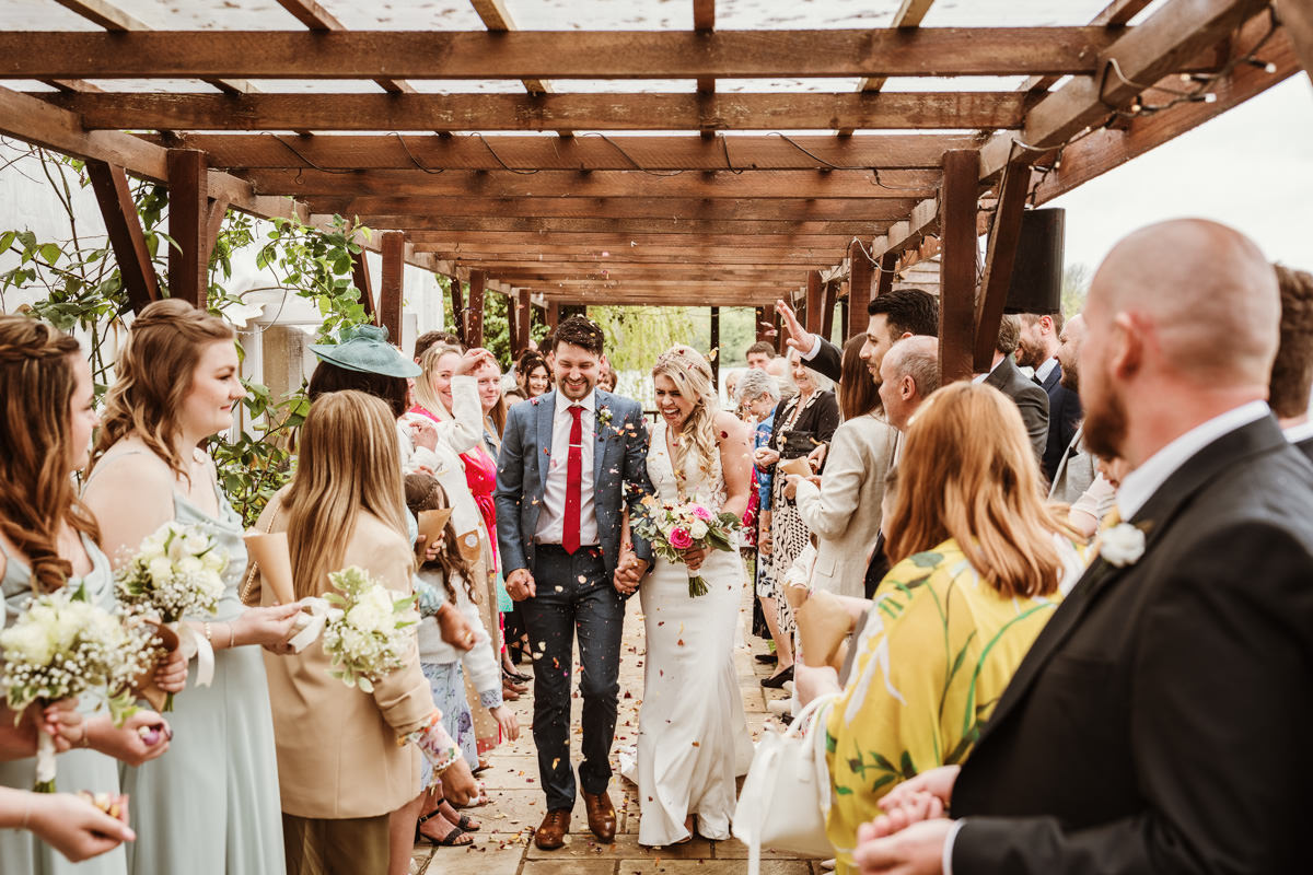 Bride and groom walking through confetti tunnel.