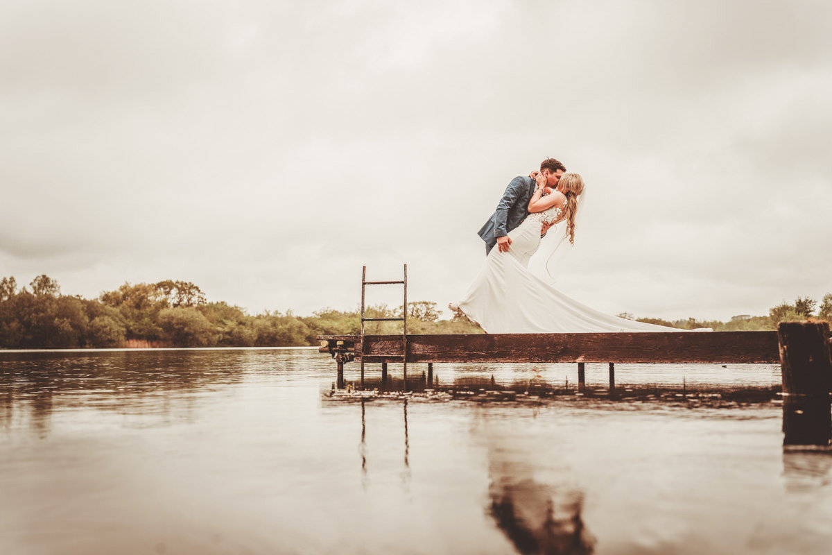 Bride and groom kissing on wooden pier
