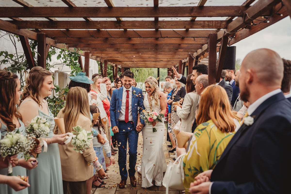 Newlyweds walk through confetti after wedding ceremony.