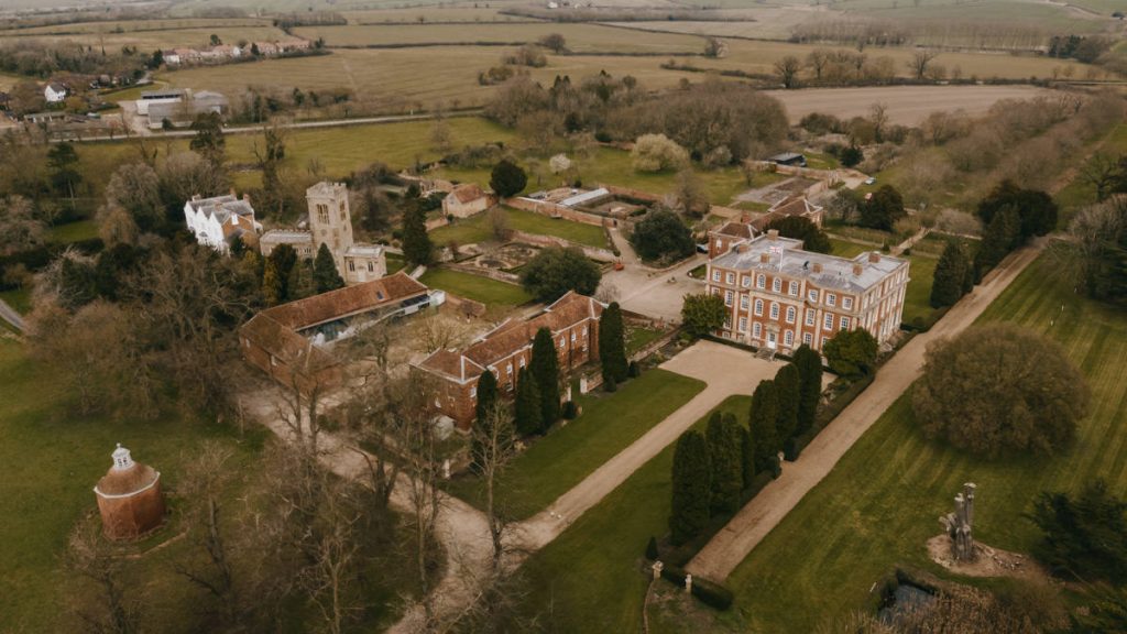 Aerial view of historic English manor and gardens.
