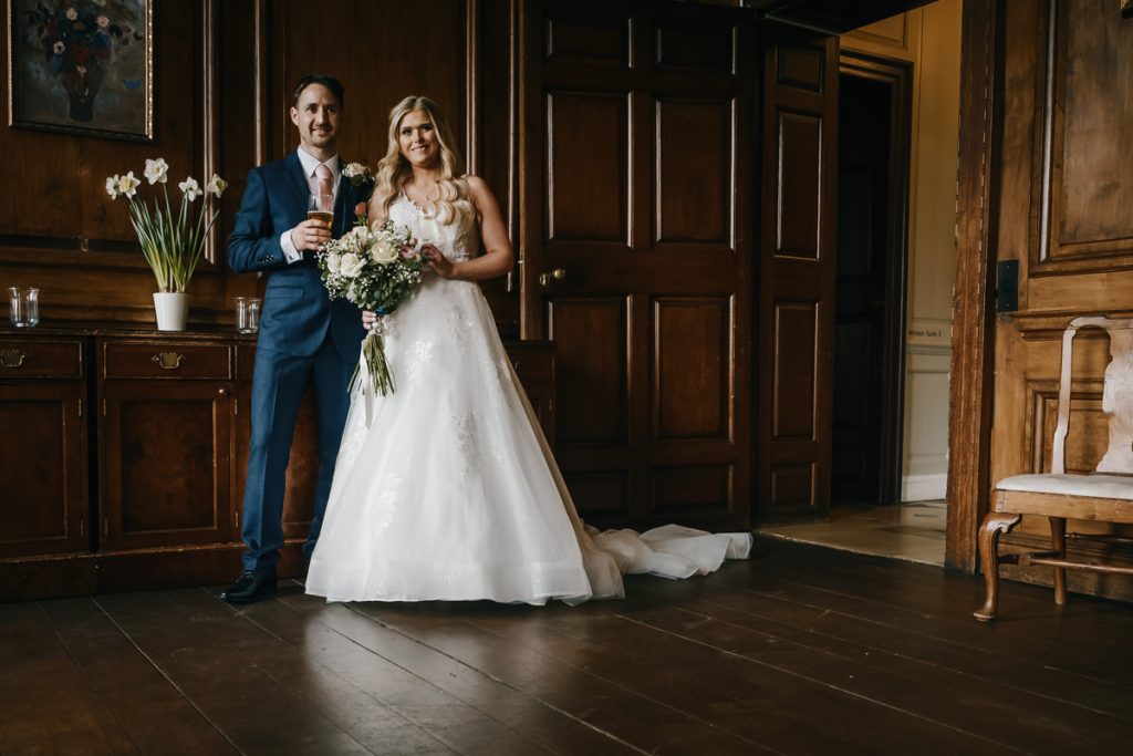 Couple posing in elegant wedding attire indoors.