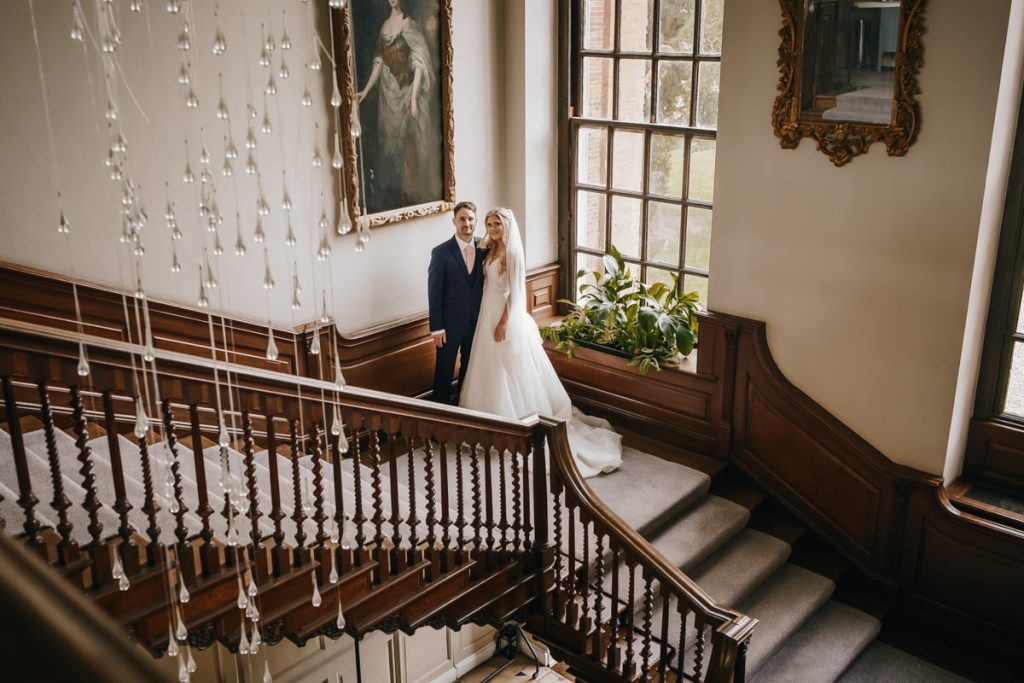 Couple posing on elegant staircase in historic building.