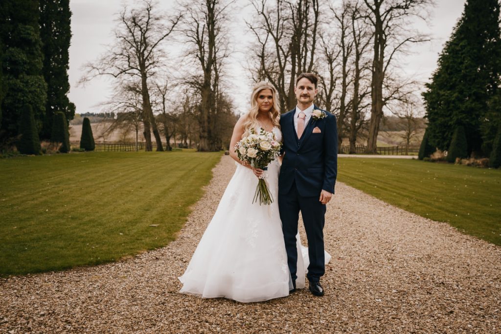Bride and groom standing on a garden path.
