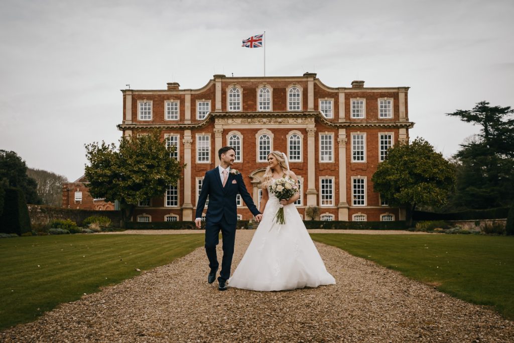 Couple walking at wedding venue, grand building background.
