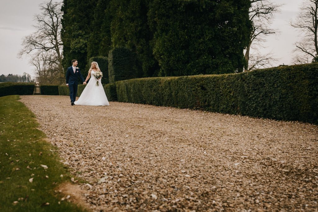 Bride and groom walking along a gravel path.