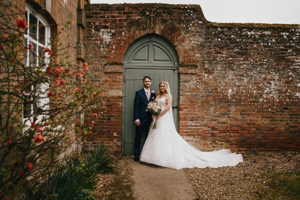 Bride and groom standing by an ancient brick wall.