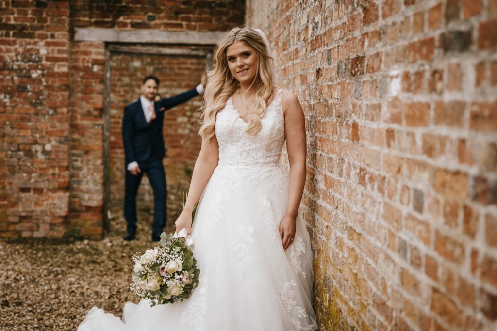 Bride with bouquet, groom in background