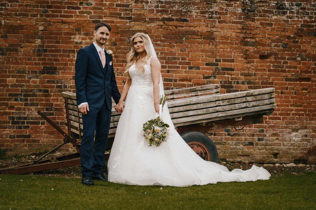 Bride and groom stand by rustic cart