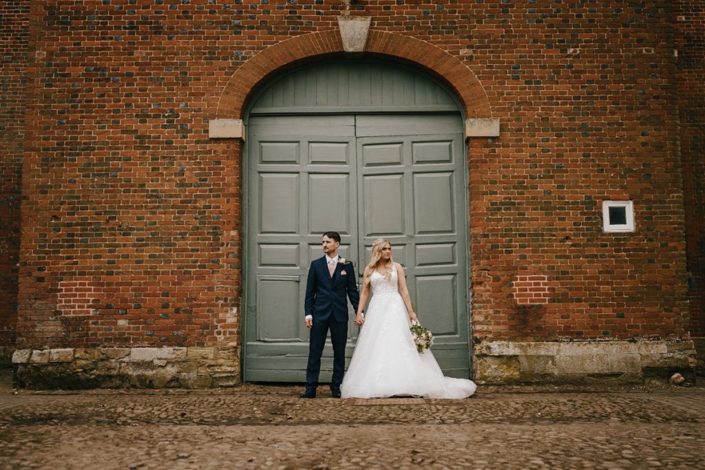 Bride and groom in front of brick wall.