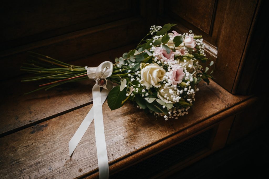 Bridal bouquet with roses on a wooden bench.