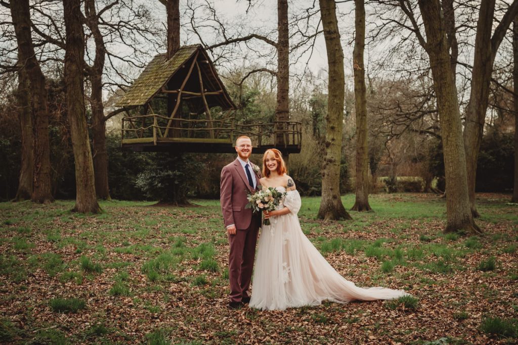 Bride and groom in forest, treehouse backdrop