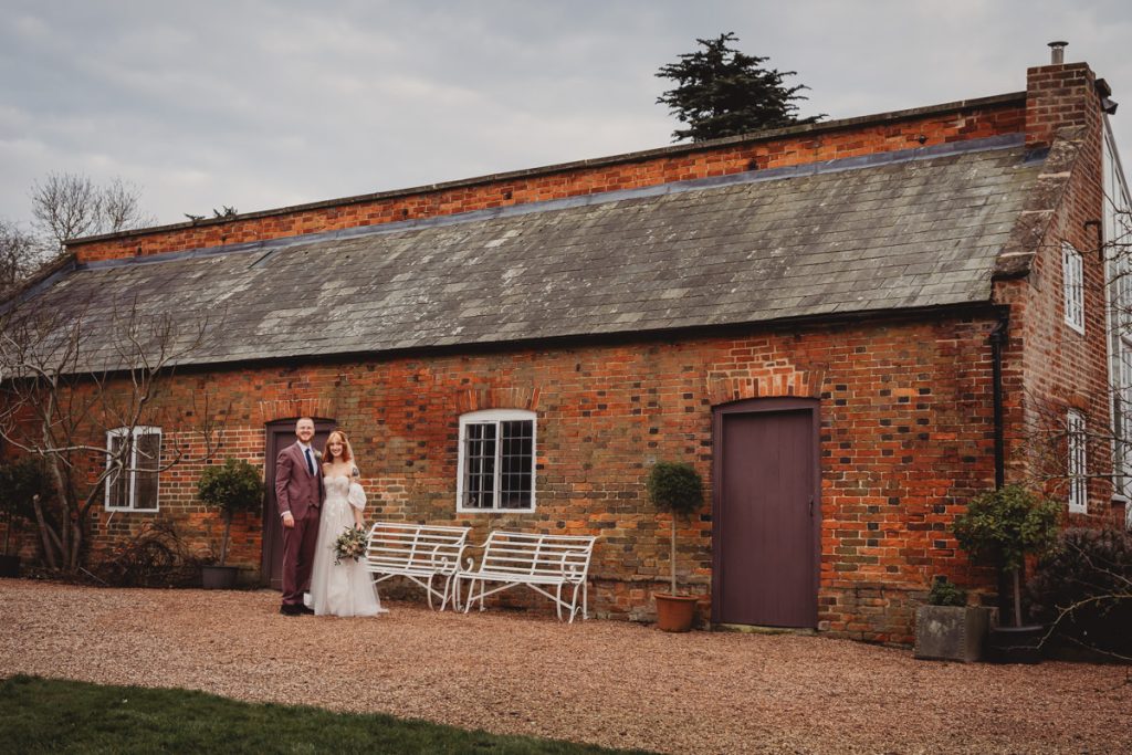 Couple standing outside rustic brick building.