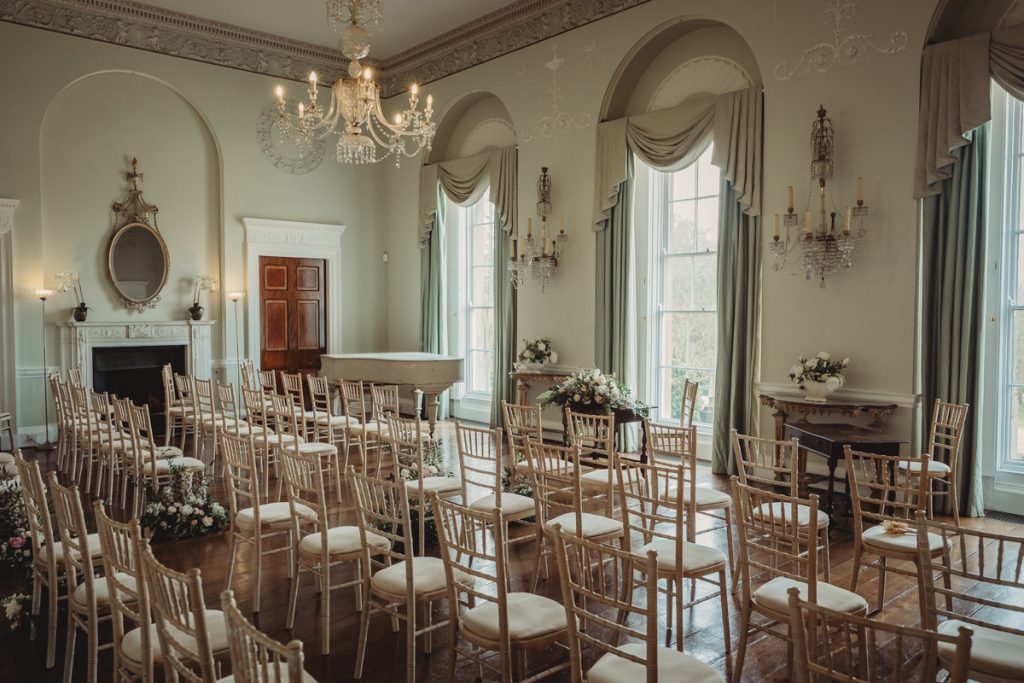 Elegant wedding venue with chandeliers and wooden chairs.
