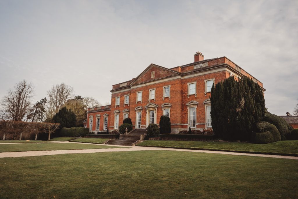 Historic red-brick mansion with green lawn.