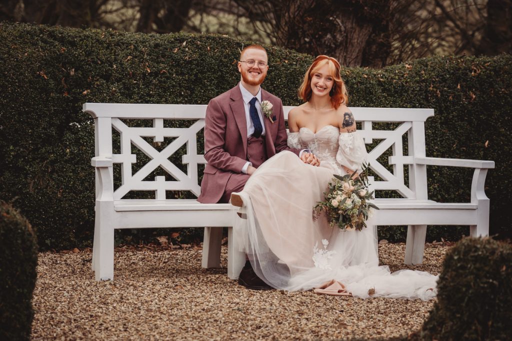 Happy wedding couple on a garden bench.