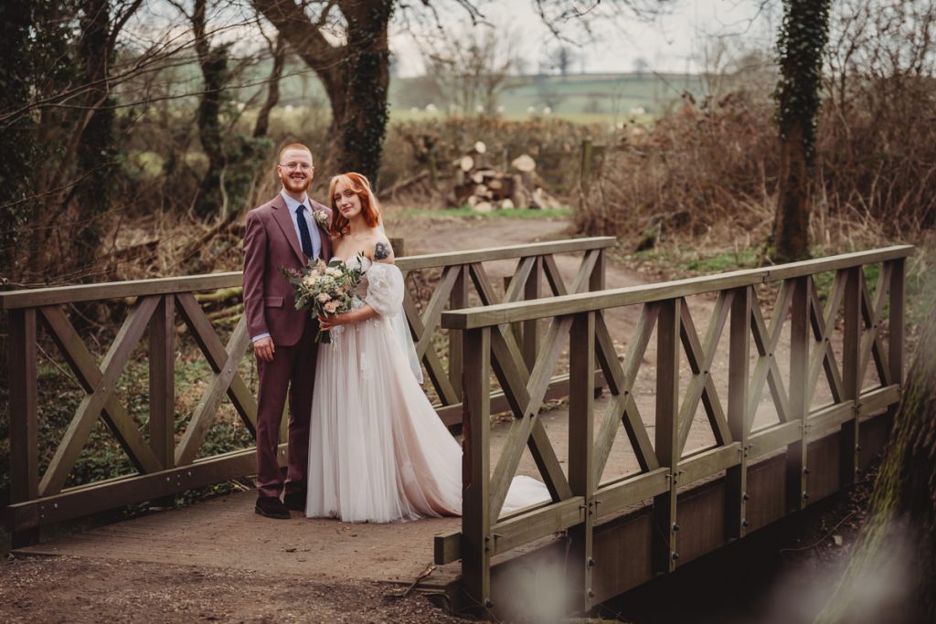 Wedding couple on wooden bridge outdoors.