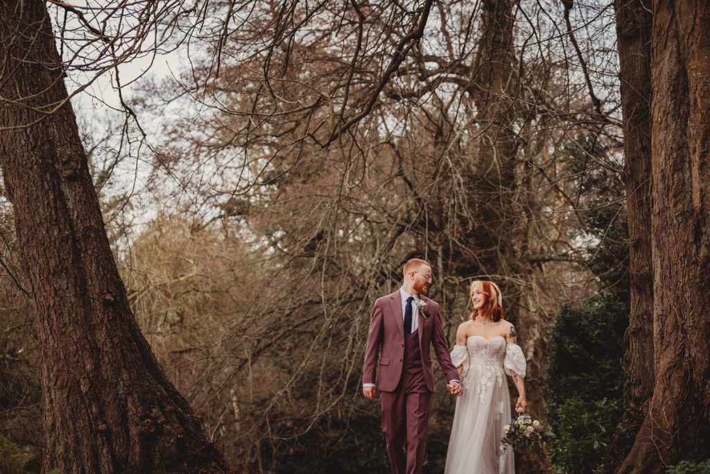 Couple walking in forest, holding hands, smiling