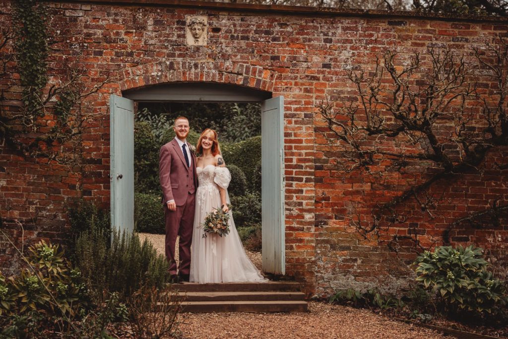 Couple posing in garden doorway dressed for an event.