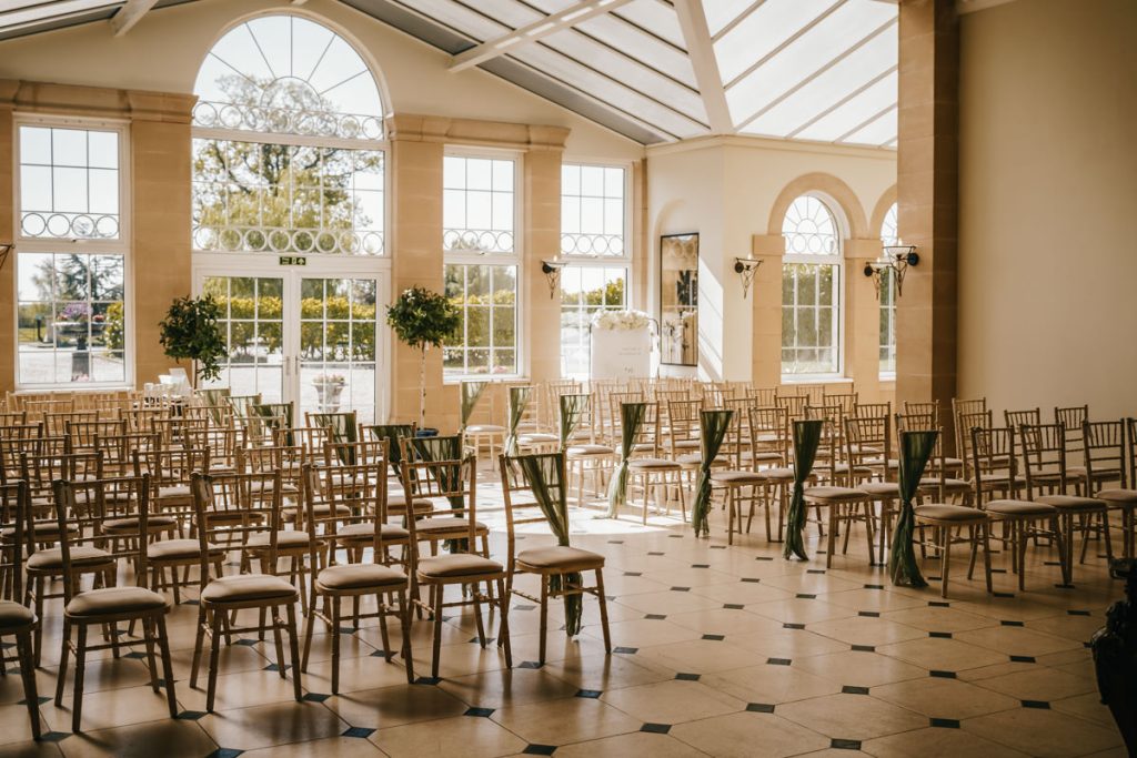 Empty sunlit wedding ceremony room with chairs at Whittlebury Park