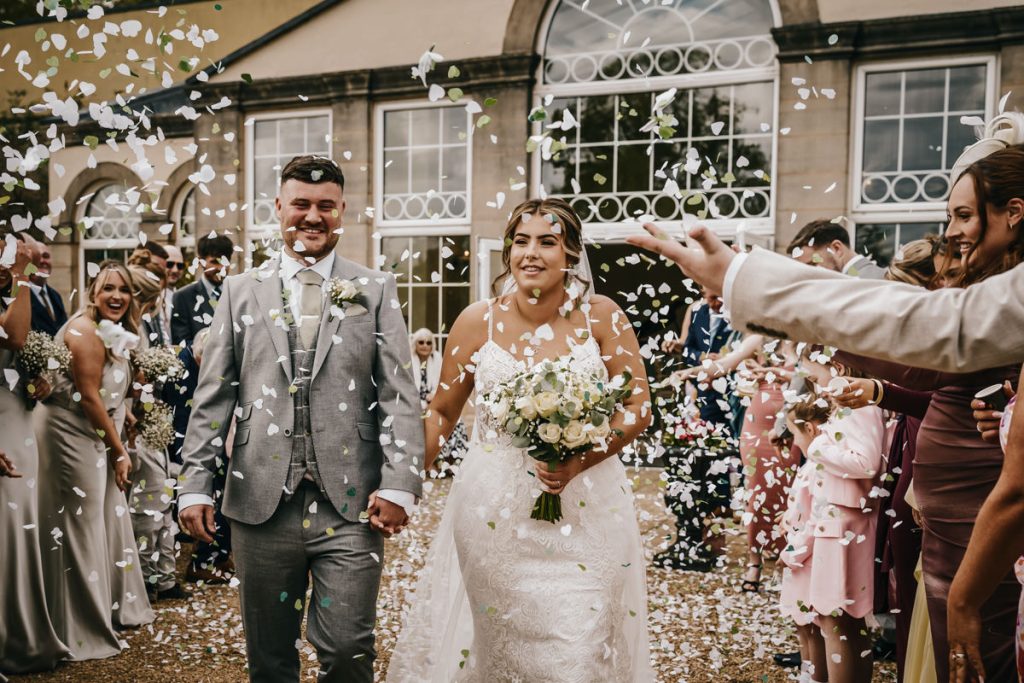 Bride and groom walking through confetti celebration at Whittlebury Park