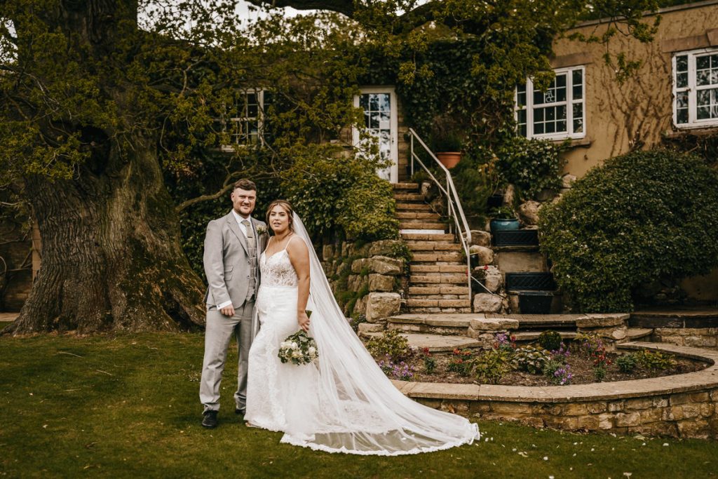 Bride and groom pose by garden stair at Whittlebury Park