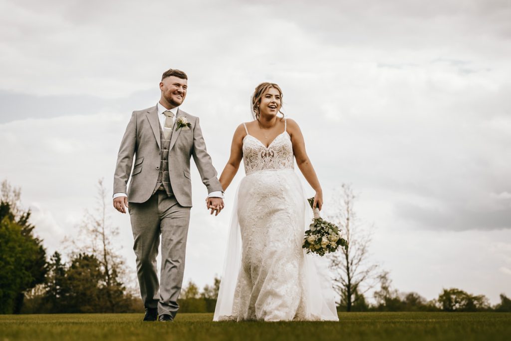 Bride and groom walking hand in hand at Whittlebury Park