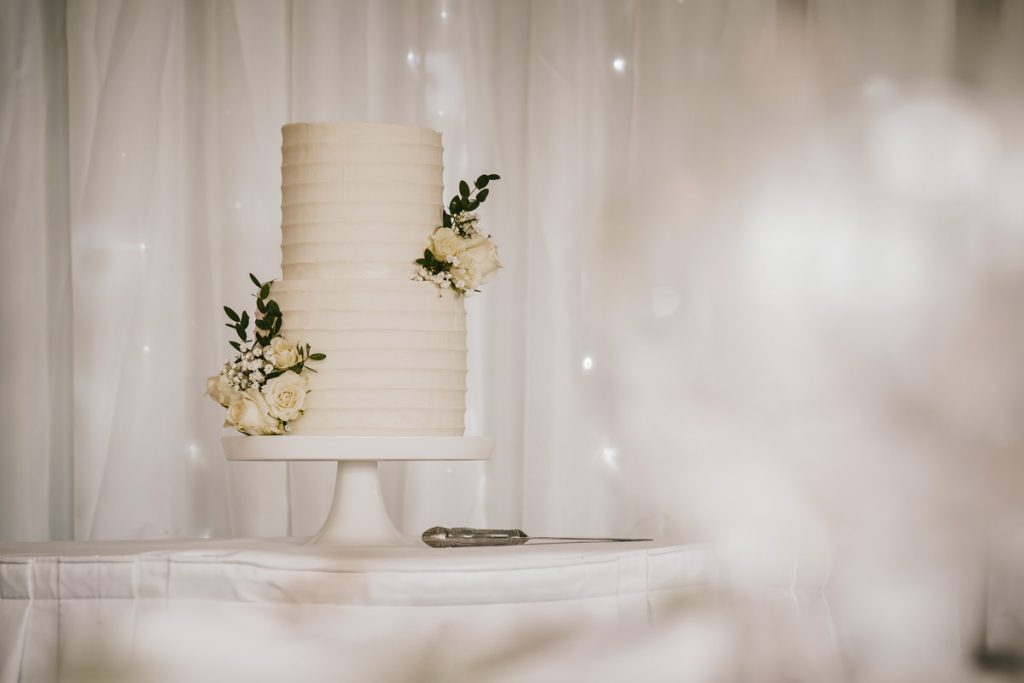 Elegant wedding cake adorned with white roses at Whittlebury Park