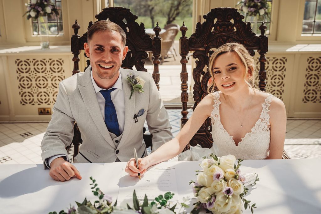 Bride and groom signing marriage certificate indoors at Kilworth House Hotel