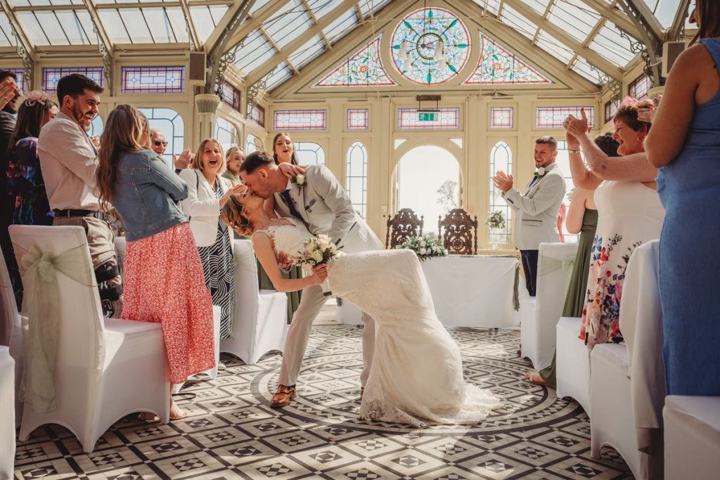 Bride and groom kissing, cheered by guests at Kilworth House Hotel