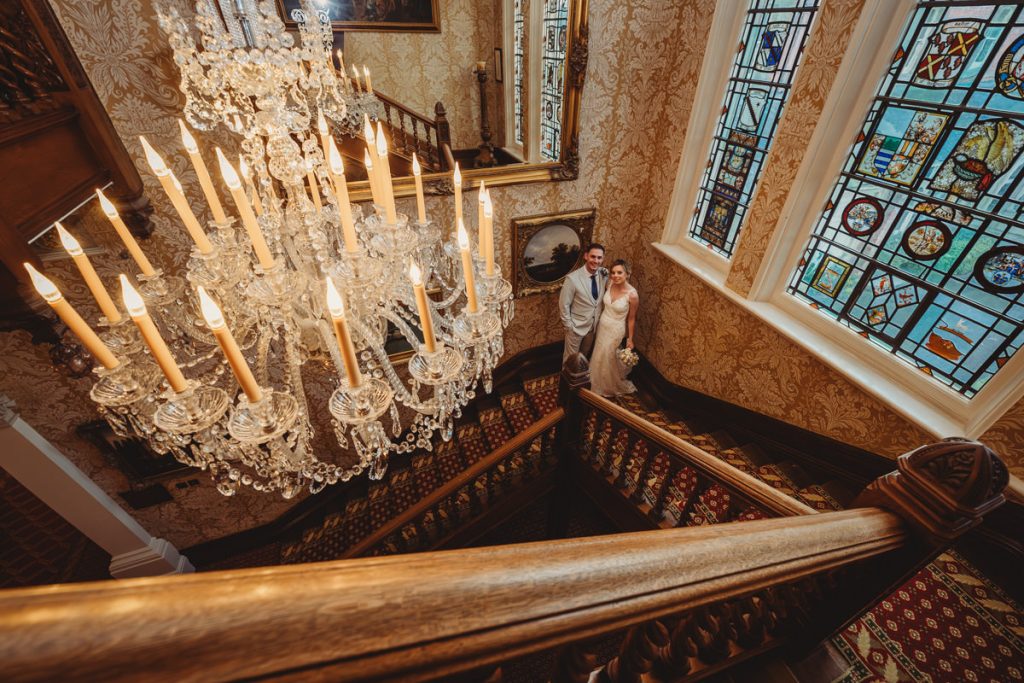Couple posing on ornate staircase under chandelier at Kilworth House Hotel