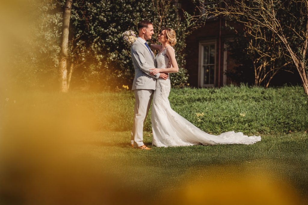 Bride and groom embracing in sunny garden at Kilworth House Hotel