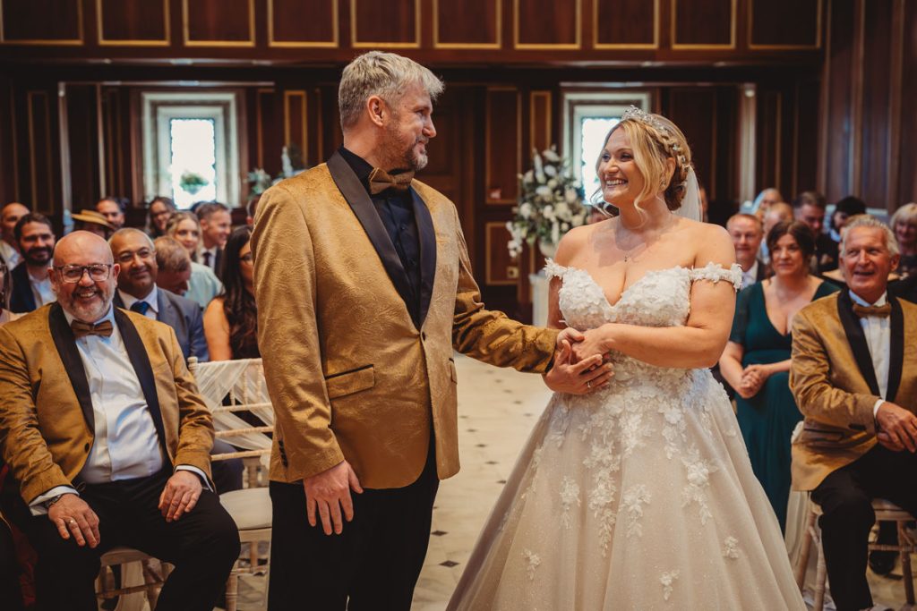 Bride and groom smiling during wedding ceremony at Bourton Hall by Tom Stenlake Photography