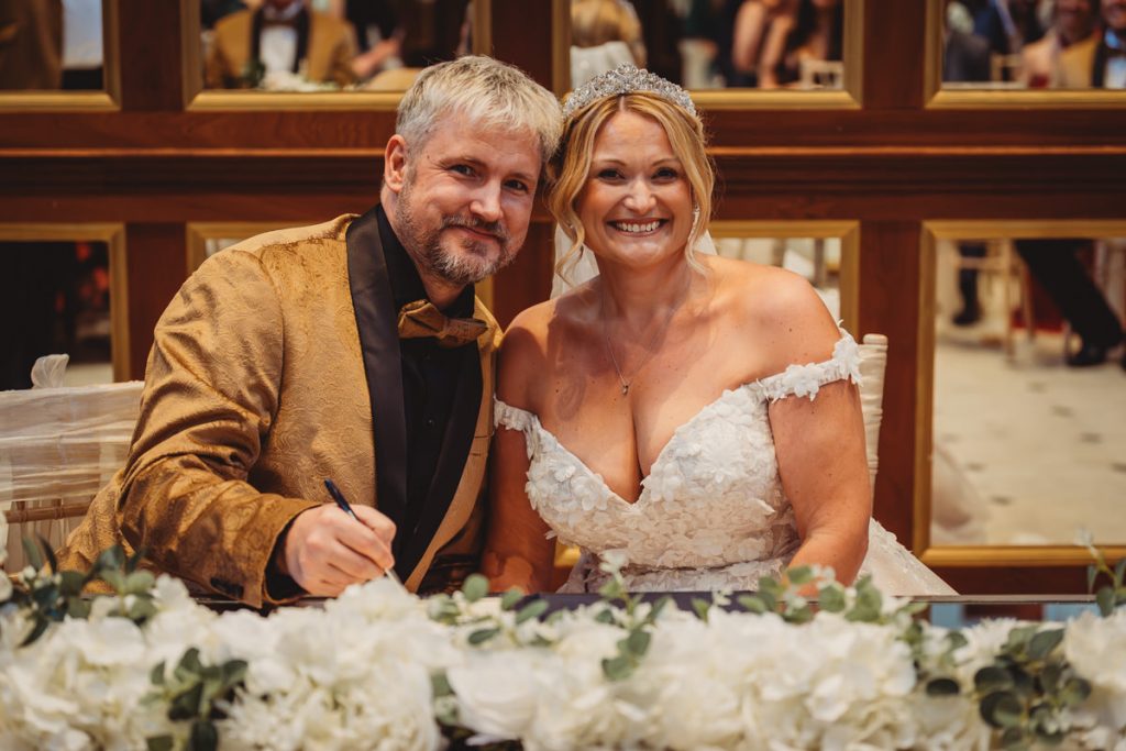 Couple smiling during wedding ceremony with flowers at Bourton Hall by Tom Stenlake Photography