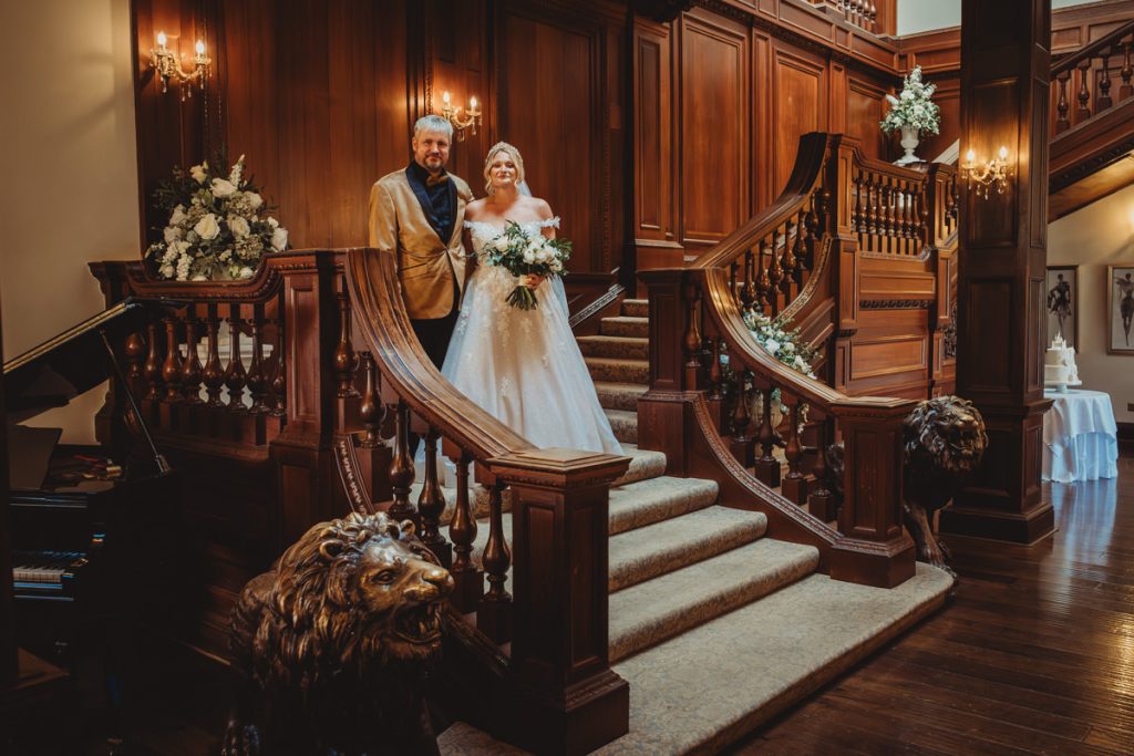 Couple on ornate staircase after wedding ceremony at Bourton Hall by Tom Stenlake Photography
