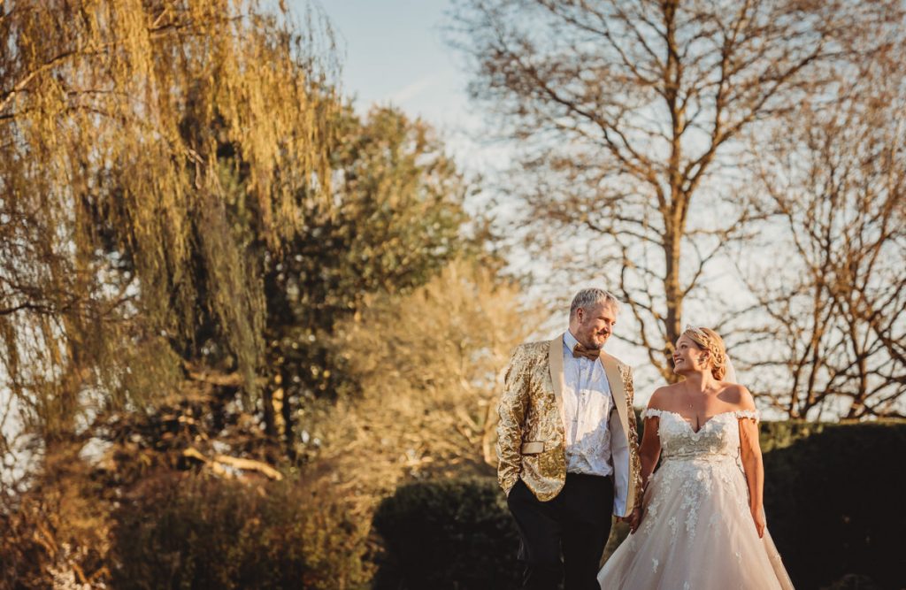 Couple in formal attire walking outdoors at Bourton Hall by Tom Stenlake Photography