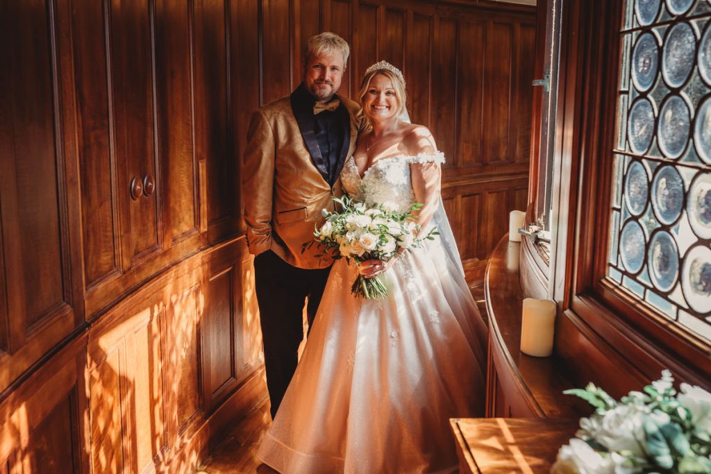 Bride and groom standing in sunlight indoors at Bourton Hall by Tom Stenlake Photography