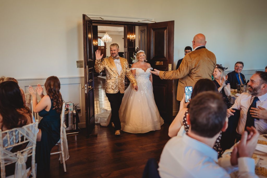 Bride and groom enter reception, guests applauding at Bourton Hall by Tom Stenlake Photography