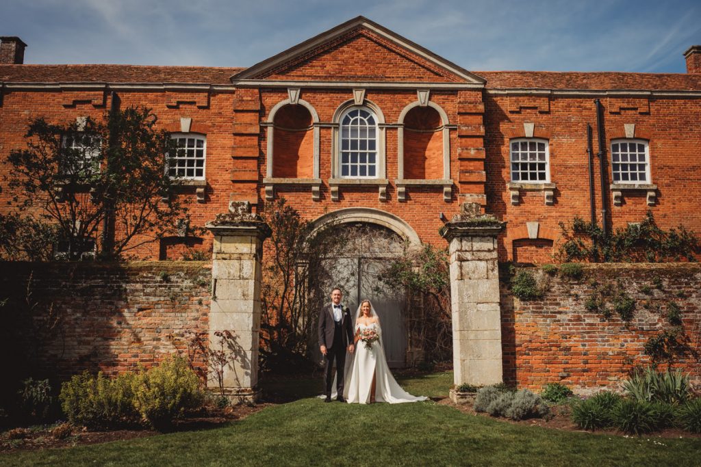 Bride and groom outside historic red brick building at Chicheley Hall