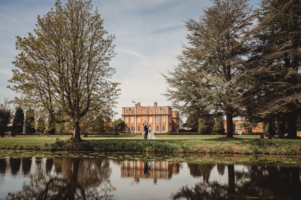 Wedding couple outside grand manor house by moat at Chicheley Hall