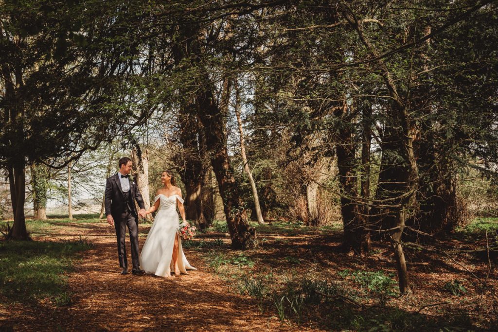 Bride and groom walking in forest path at Chicheley Hall