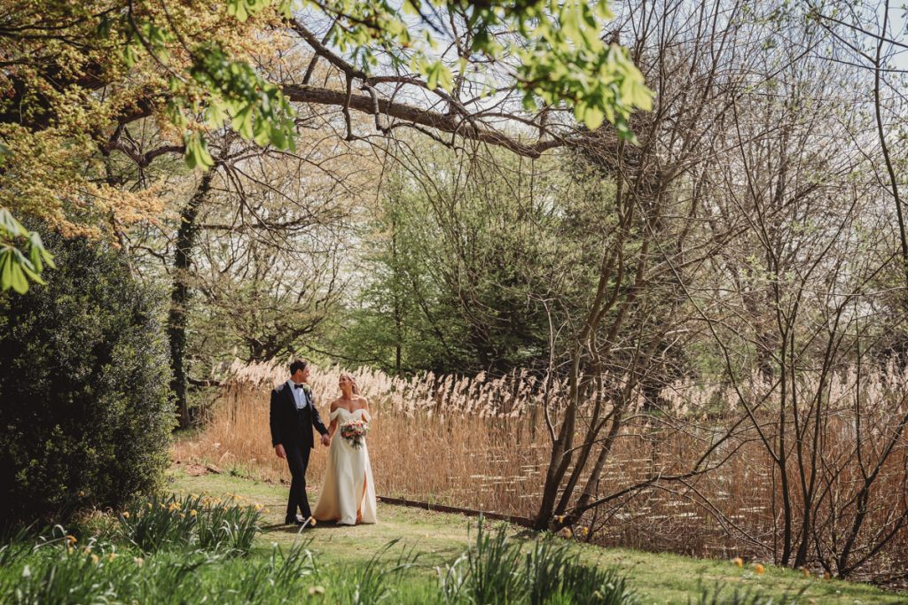 Couple walking in lush garden scenery, holding hands at Chicheley Hall