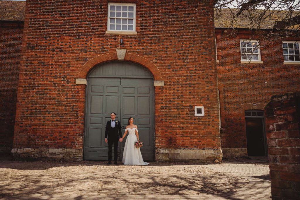 Couple holding hands outside a brick building at Chicheley Hall