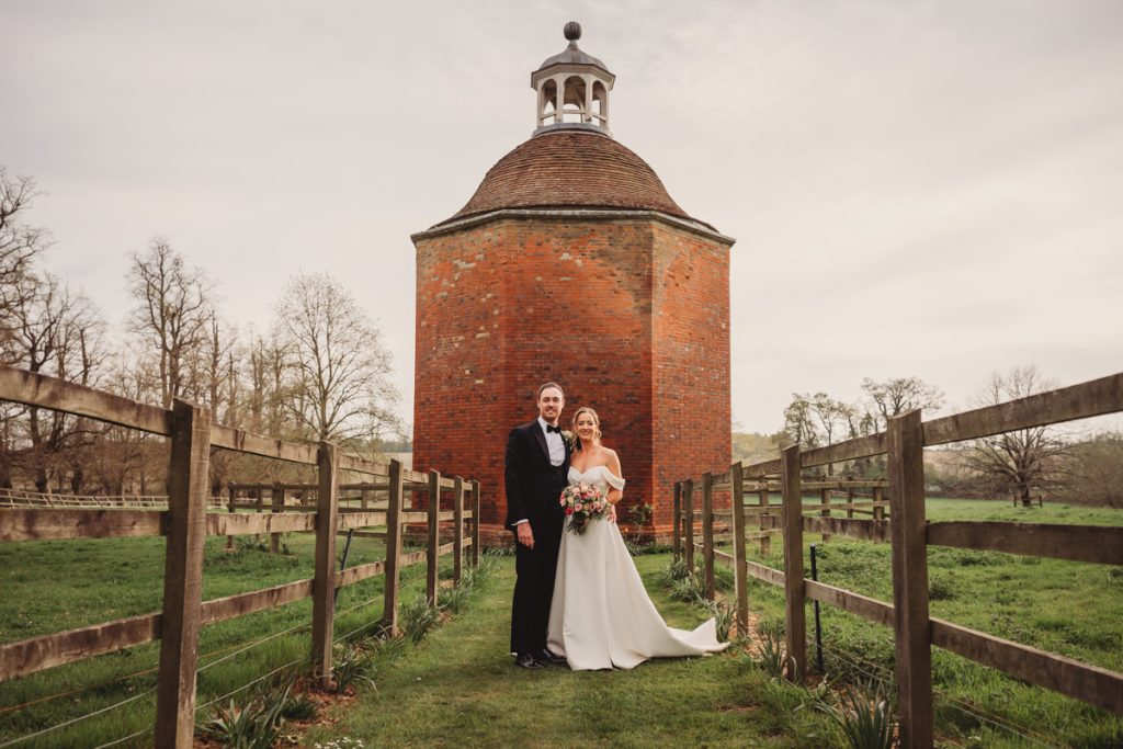 Bride and groom near tall brick folly at Chicheley Hall