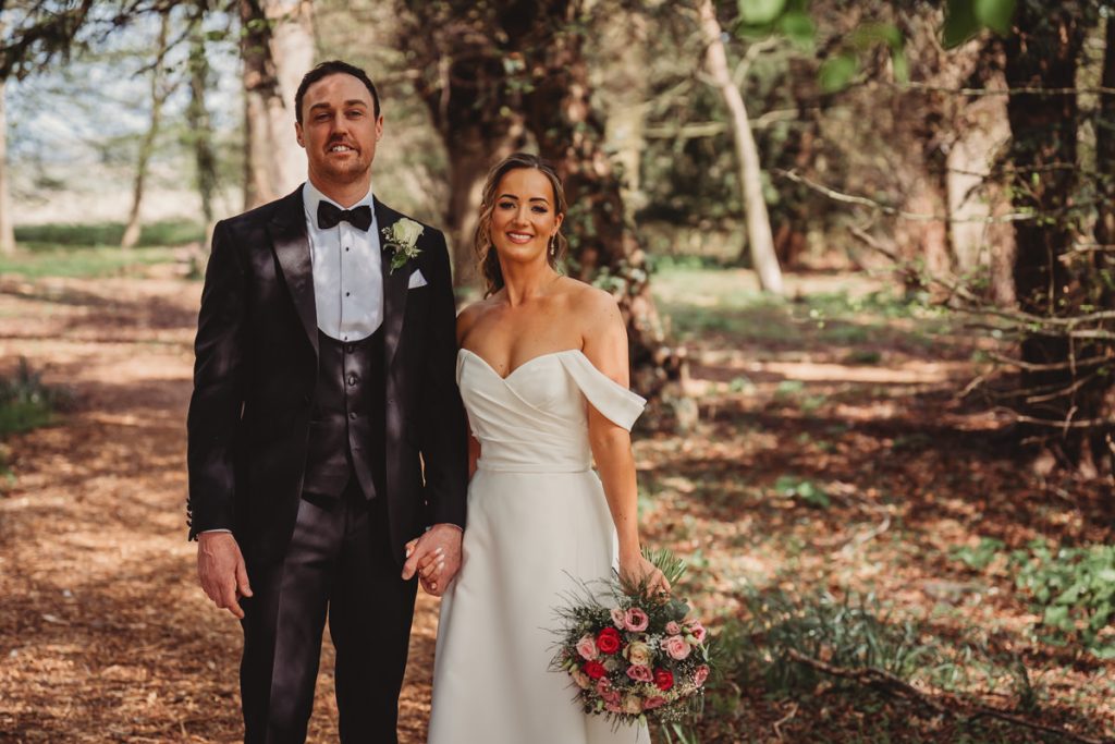 Bride and groom smiling in wooded area at Chicheley Hall