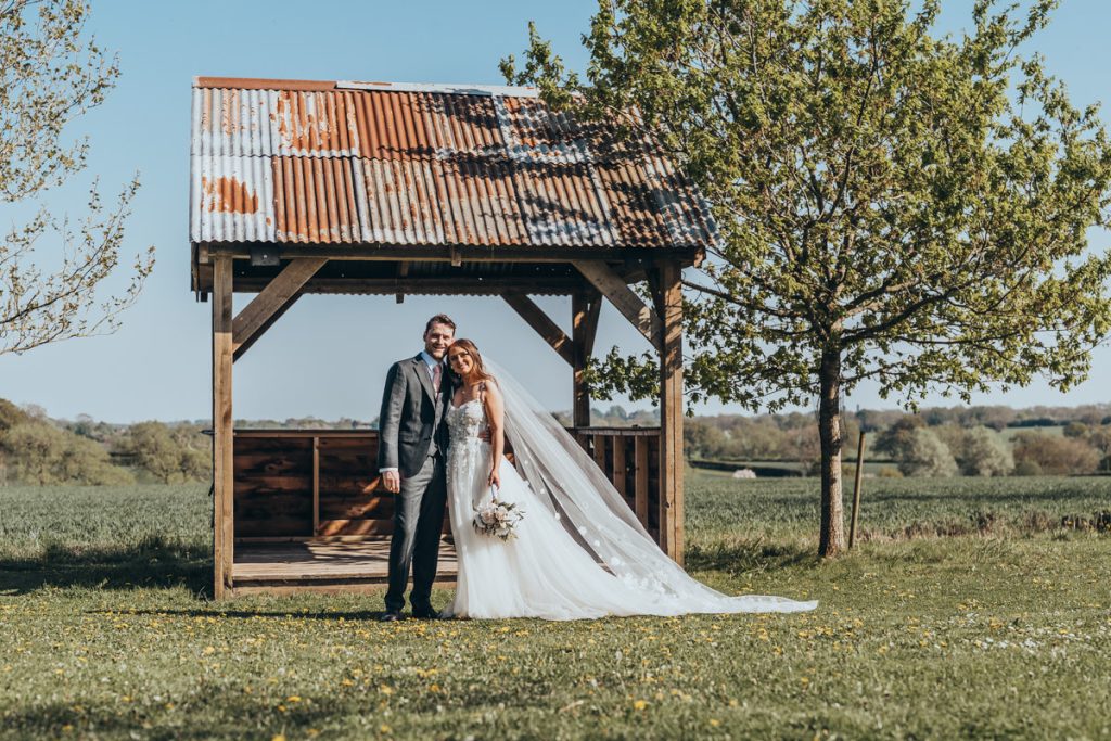 Wedding couple under rustic shelter in countryside at Huntsmill Farm