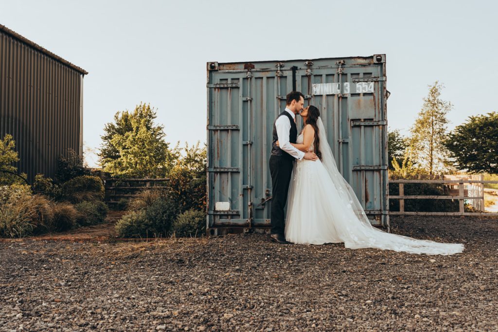 Bride and groom kissing by shipping container at Huntsmill Farm