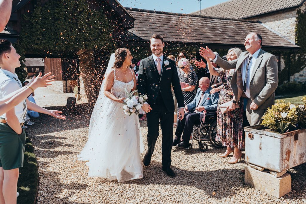 Newlyweds walking through guests throwing confetti at Huntsmill Farm