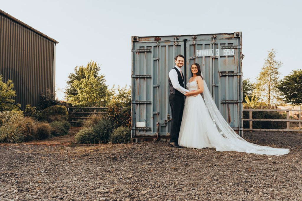 Bride and groom beside rustic shipping container