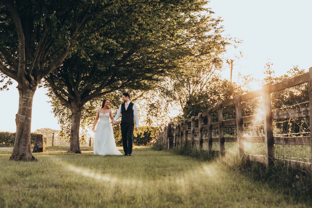 Bride and groom walking in garden at sunset at Huntsmill Farm